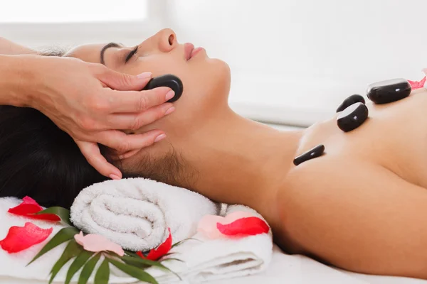 Beautician make stone massage spa for woman at wellness center