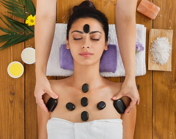 Beautician make stone massage spa for woman at wellness center