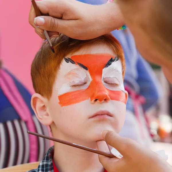 Child boy face painting, making tiger eyes process