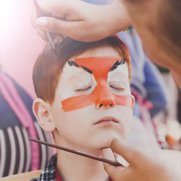 Child boy face painting, making tiger eyes process