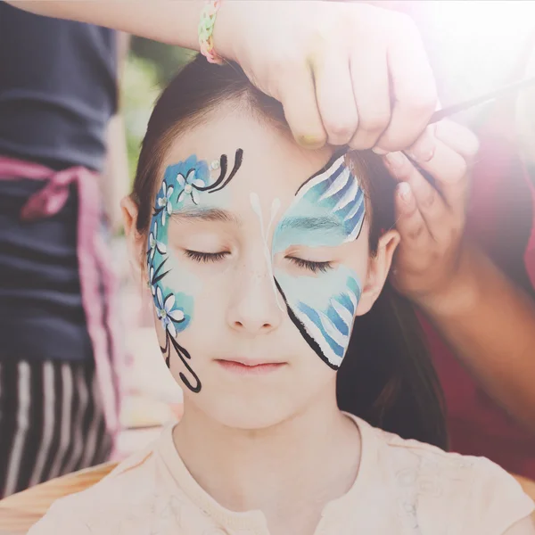 Female child face painting, making butterfly process