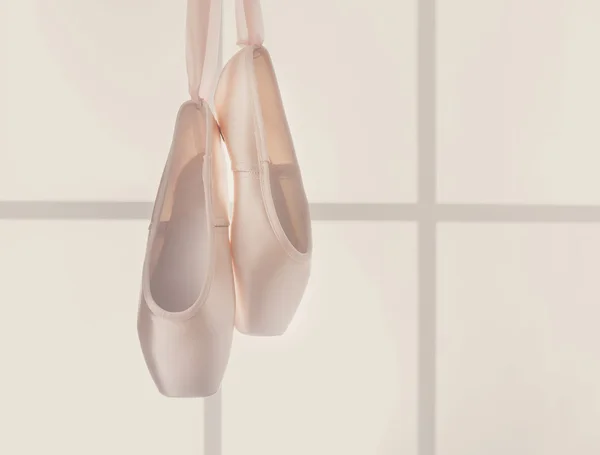 Pink ballet pointe shoes hanging on window