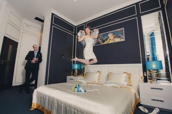 Happy bride jumping on a hotel bed