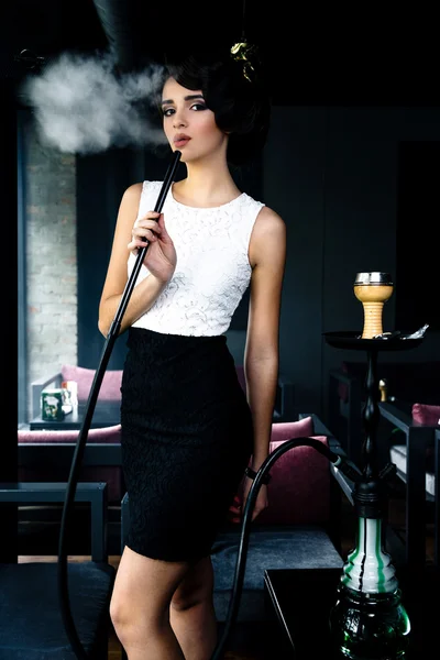 Woman smokes a hookah in cafe