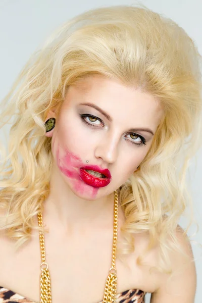 Woman with makeup smearing lipstick.