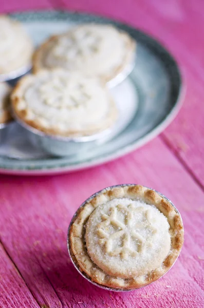 Festive shortcrust pastry mince pies. A sweet mince pie, a traditional rich festive food on pink wooden background.