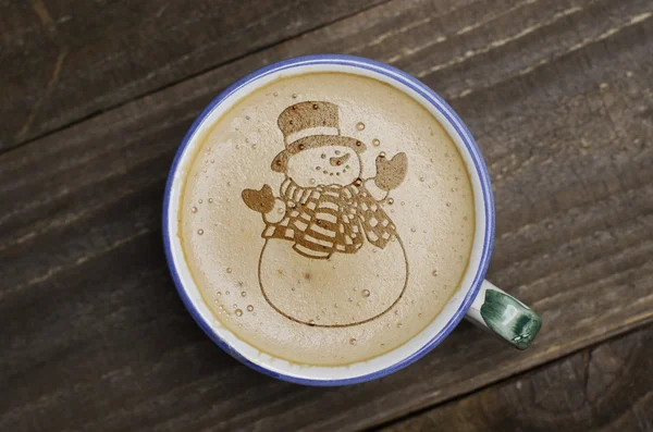 Cup of coffee latte art on wood table. Foam form of snowman.