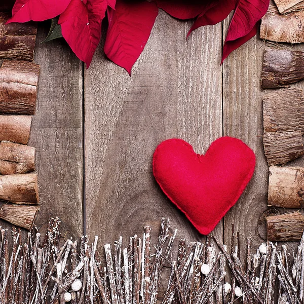 Frame arranged from poinsettia flowers, sticks, twigs, driftwood, coconut shell as a background. Handmade from felt red heard. Craft.