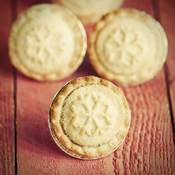 Festive shortcrust pastry mince pies. A sweet mince pie, a traditional rich festive food on red wooden background.