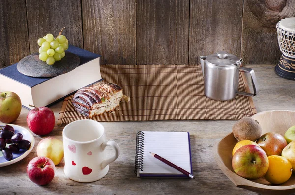 Pencil and notebook with copy space on wooden table. Healthy breakfast concept. Fruits and drink.