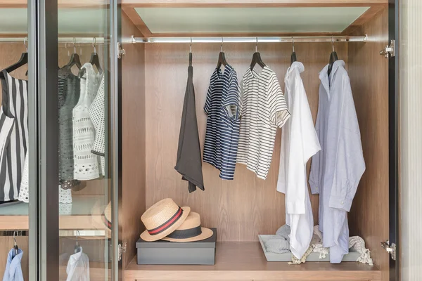 Shirts and suite hanging on rail in wooden wardrobe