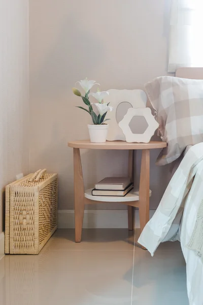 Vase of flower and picture frame on wooden table side in bedroom