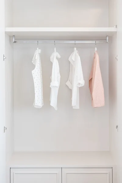 Shirts hanging on rail in white wooden wardrobe