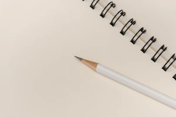 White pencil with blank notebook on white