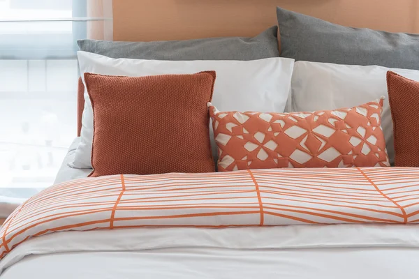 Orange color tone pillows set on bed in modern bedroom
