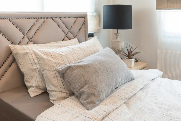 Single bed in modern bedroom with black lamp and vase of plants