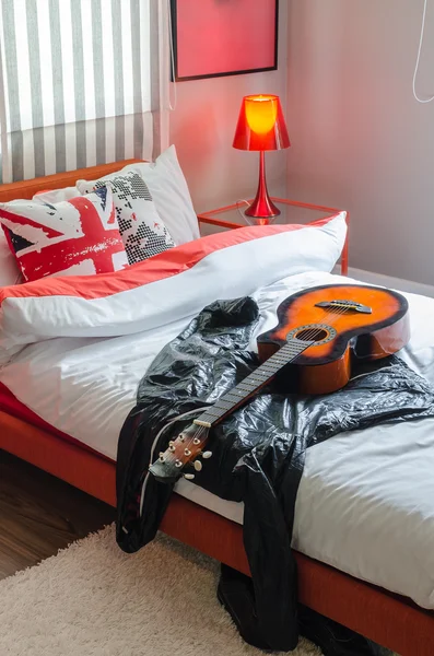 Modern bedroom with guitar and jacket on white bed