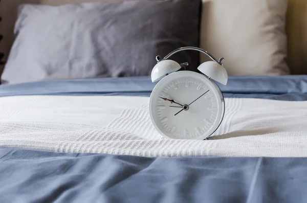 Modern white alarm clock on modern bed