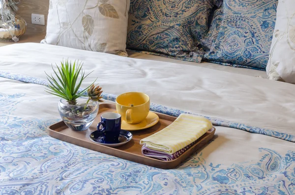 Wood tray of tea cup and plant on bed