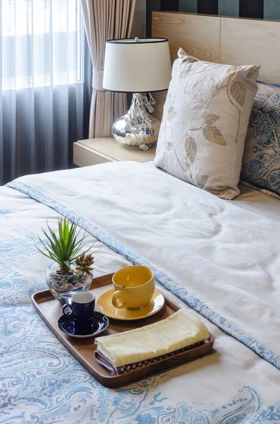 Wood tray of tea cup and plant on bed