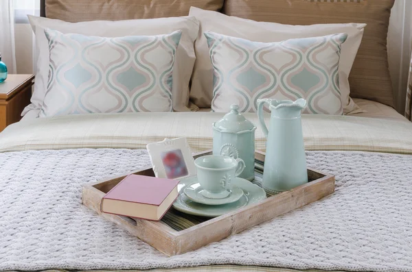 Wood tray of tea cup set and book on bed