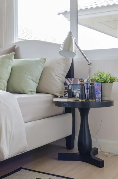 Green pillows on bed with round wooden table