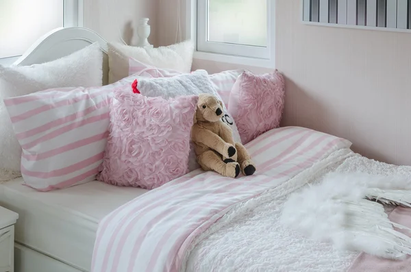 Kid\'s bedroom with doll and pink pillows on bed