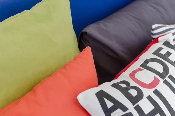 Row of colorful pillows on bed