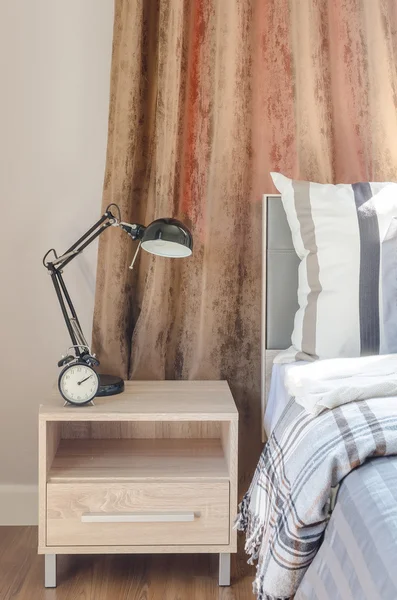 Modern black lamp with black clock on wooden table in bedroom