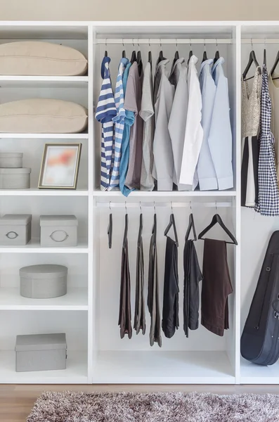 Clothes hanging in white wardrobe