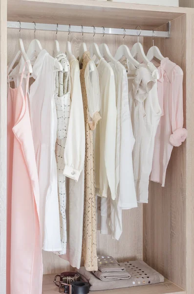 Clothes hanging in wooden wardrobe