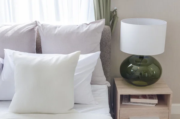 White pillows on modern white bed with modern lamp
