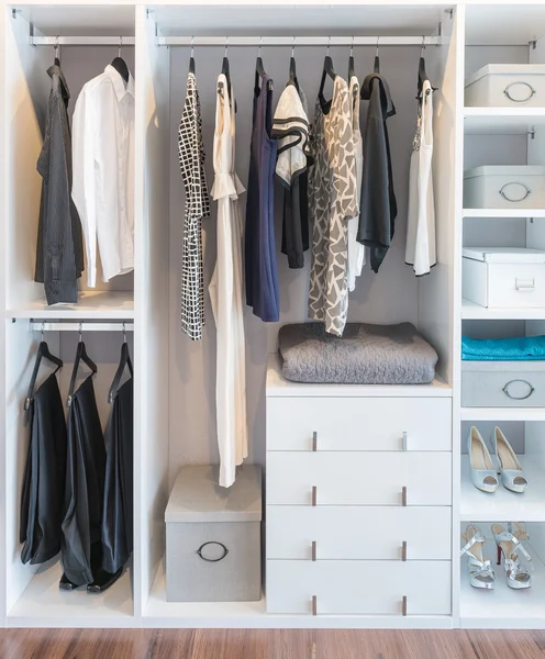 Clothes hanging on rail in white wardrobe