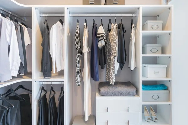Clothes hanging on rail in white wardrobe