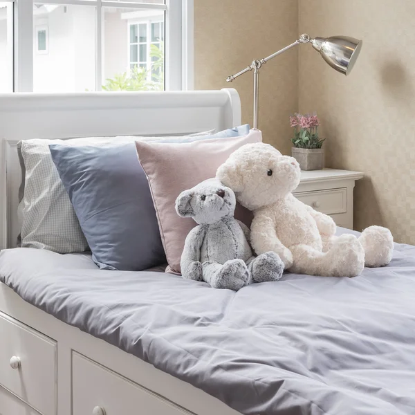 Kid\'s bedroom with dolls on white wooden bed