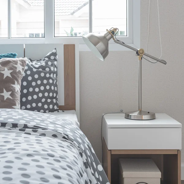 Modern lamp on bedside table with wooden bed