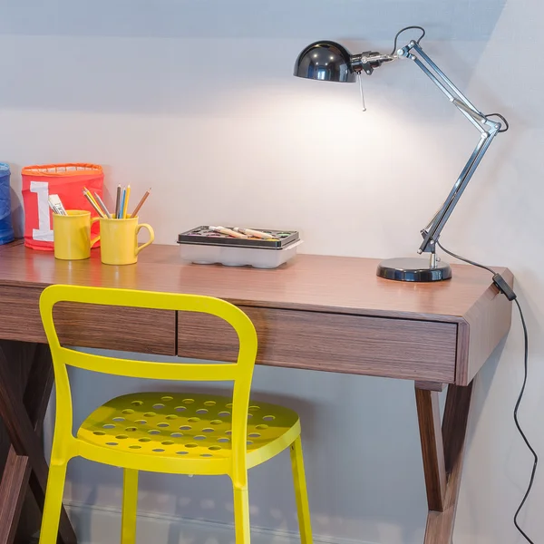 Yellow chair and wooden desk with modern black lamp