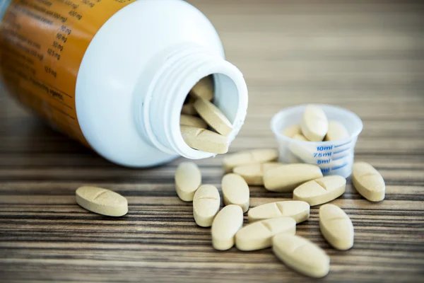 Brown pills an pill bottle on the table. Vintage Tone.