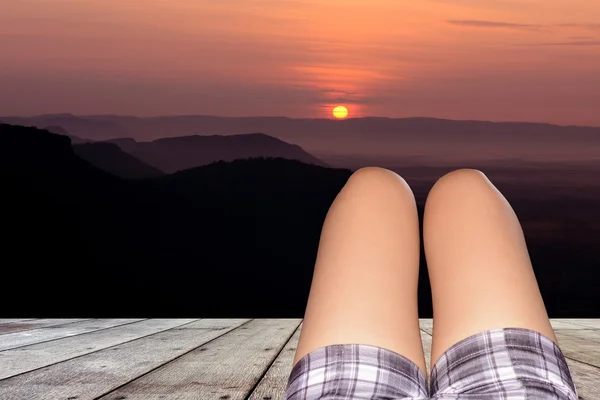 The legs of a woman lying on a wooden floor after sunset .