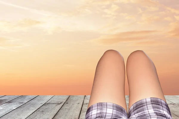 The legs of a woman lying on a wooden floor after sunset .