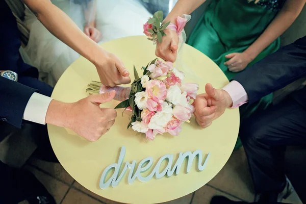 Group with hands together there is a wedding bouquet on a tableland by volume letters