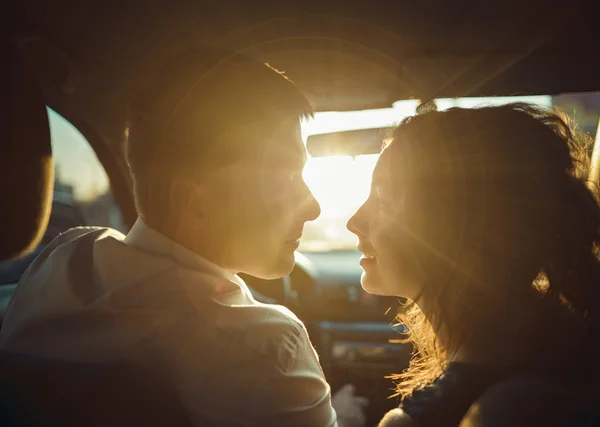 Silhouette of couple in the sun for a moment before a kiss,wide angle in car