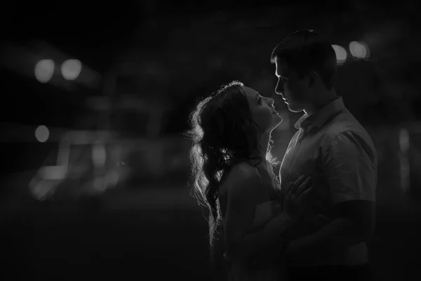 Couple standing in an embrace facing each other, night photo,black and white