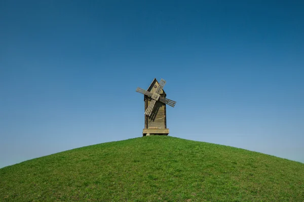 Landscape with wooden windmill on a green hill, horizontal photo
