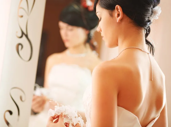 Bride standing opposite to a mirror