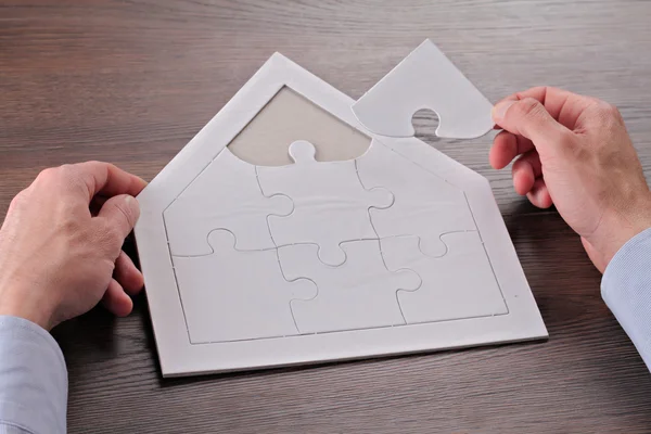 Happy family, home, insurance concept. Man building house shape blank puzzle