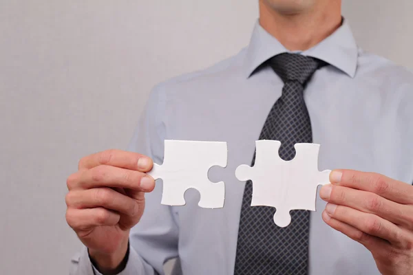 Business solutions, partnership concept. Businessman holding two pieces of a blank puzzle