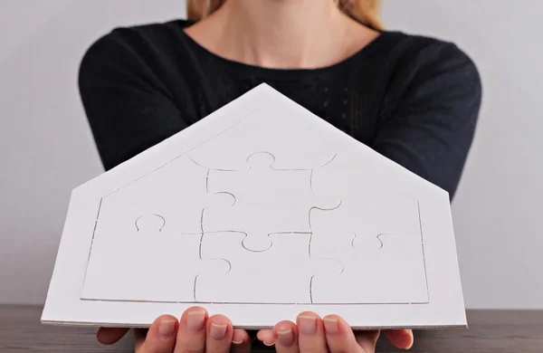 Happy family values, home insurance,real estate investment  concept. Woman holding house shape blank puzzle. Copy space image