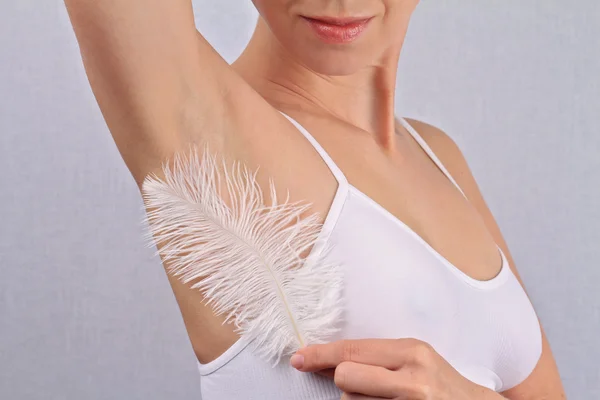 Armpit waxing, laser hair removal. Young woman holding her arms up and showing underarms, armpit, ideal smooth clear skin