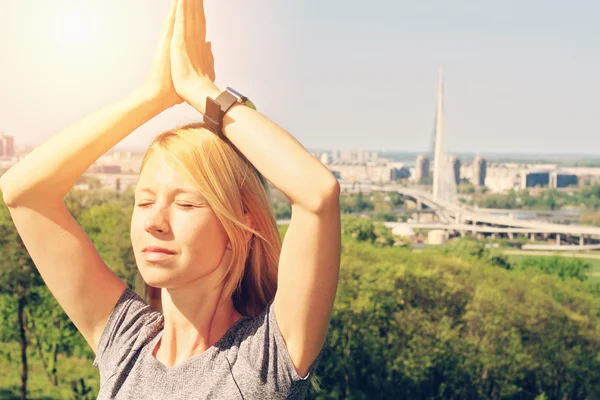 Yoga in the city : Woman meditating in yoga position in nature /